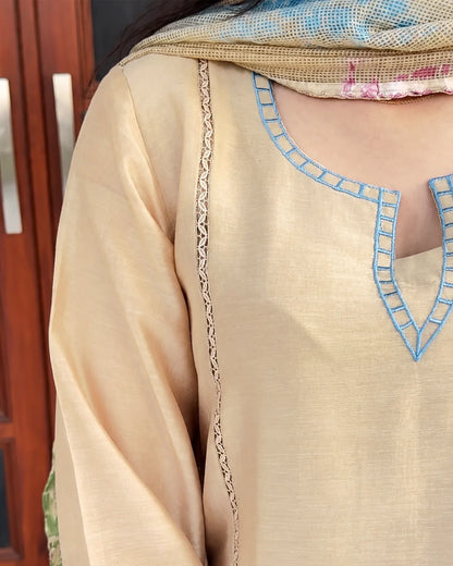Close-up of a beige or cream-colored traditional tunic with light blue embroidered neckline details and a matching patterned dupatta draped over the shoulders.