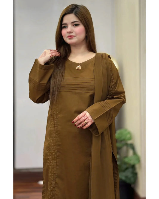 A woman wearing a long-sleeved brown modest dress with a matching draped shawl, standing in an indoor setting.